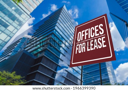 An offices for lease sign in front of a modern glassy commercial Grade A building.