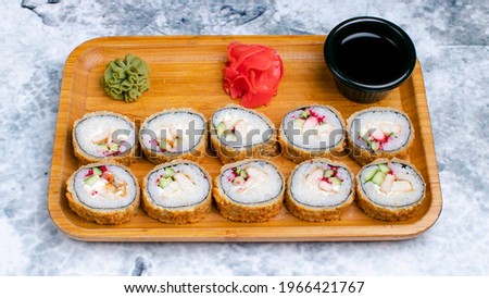 Chicken hot sushi rolls with wasabi, gari and soy sauce on wooden tray isolated on marble.