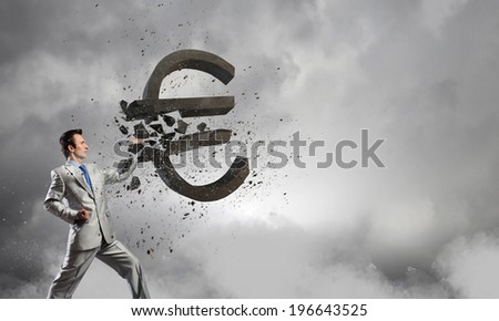 Businessman breaking stone euro symbol with karate punch