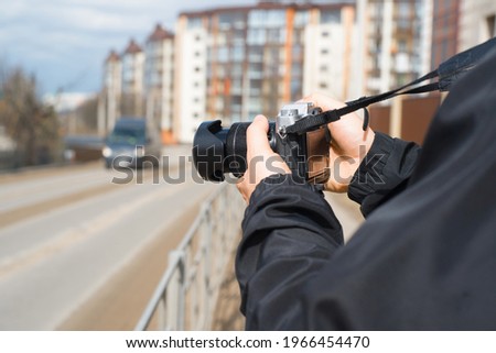 Photographer using a camera outdoors during the day. Close-up of hands holding a photo camera.