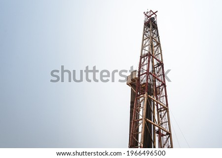 Oil drilling rig derrick platform structure with blue sky background. Heavy industrial operation and energy business photo.