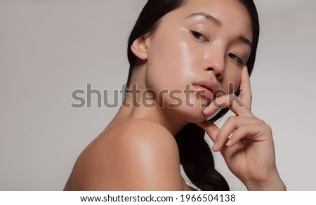 Young asian woman with glowing skin looking away with an attitude. Female with beautiful skin against beige background. Royalty-Free Stock Photo #1966504138