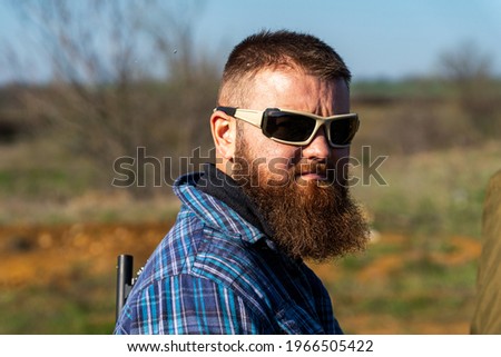 Portrait of a man with a beard and glasses, shoots a shooter at a shooting range, soft focus, there is a little creative noise in the photo Royalty-Free Stock Photo #1966505422