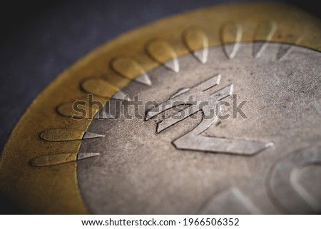 Translation of the inscription: rupee. Fragment of Indian 10 rupee coin with the sign of the national currency. Dramatic illustration with vignetting. Money, economy and banking in India. Macro