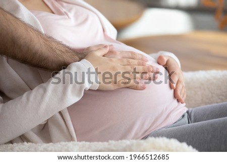 Crop close up of young multiracial parents touch wife baby bump wait expected for kid child to be born. Happy diverse couple enjoy easy healthy pregnancy time together at home. Parenthood concept. Royalty-Free Stock Photo #1966512685