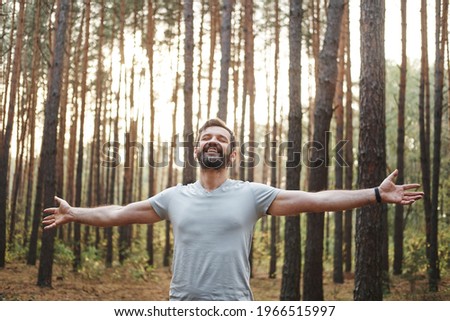 Young happy Caucasian male in the forest. He spread his arms and closed his eyes. Wellness concept and holistic rest Royalty-Free Stock Photo #1966515997