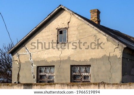 Deep cracks in facade of house. Sample of low-quality work. Topic: errors in construction of walls and foundations, destruction. Royalty-Free Stock Photo #1966519894