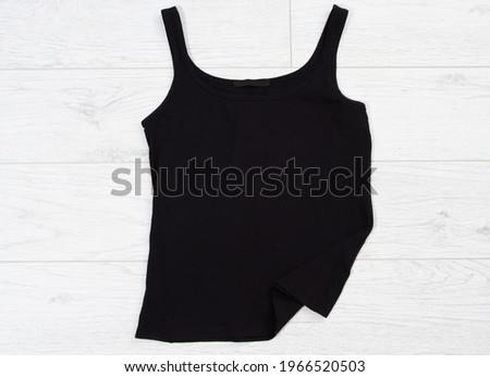 Black tank top tshirt template mock up on white wooden background top view.