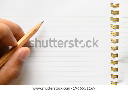 Man hand using a pencil writing ,drawing on a white book,letter