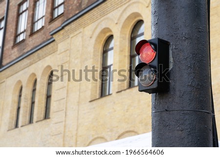 Red Light on a small traffic light attached on a gray pillar, a brick house in the background. Prohibition of driving machines, No passage сoncept
