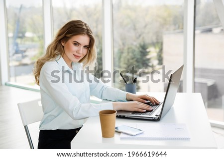 Young beautiful businesswoman works in the office with a laptop. Success concept  Royalty-Free Stock Photo #1966619644