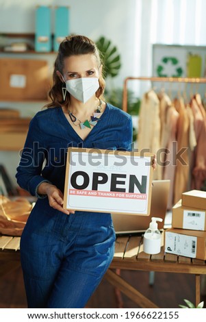 modern small business owner woman with ffp2 mask, open after covid sign and antiseptic in the office.