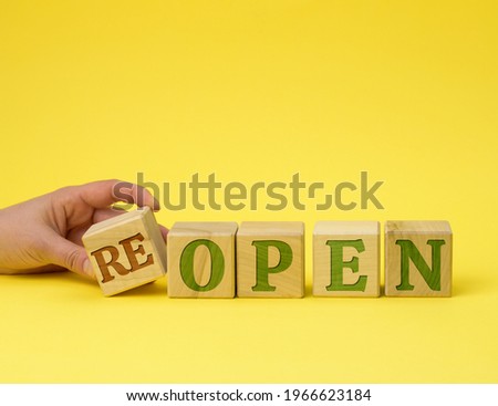 hand holds a stack of wooden cubes on the reopen inscriptions. The concept was opened after restructuring, renovation, lockdown. Welcome, return to normal work rhythm