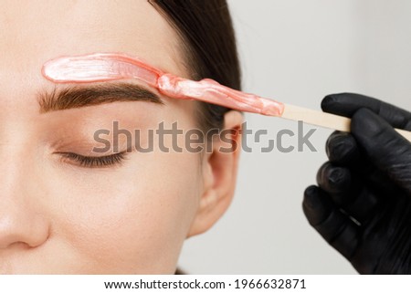 Makeup artist does facial hair removal procedure. Styling and lamination of eyebrows. Stylist's hands. Woman doing eyebrow permanent makeup correction. Microblading brow. Melted wax. Royalty-Free Stock Photo #1966632871