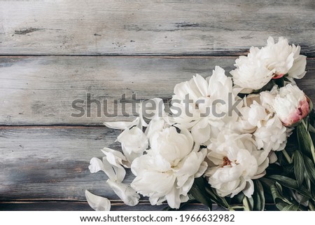 Feminine wedding table composition with white peonies flowers on old shabby wooden background. Empty copy space. Flat lay, top view. Picture for blog. Floral corner. Styled stock photo. 