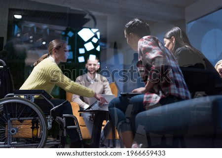 Office workers and person in a wheelchair discussing business moments in a modern office. Disability and business concept Royalty-Free Stock Photo #1966659433