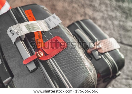 Two suitcases at airport with heavy tag closeup. Checked suitcase and carry-on luggage on the curbside ready for travel with address tags.