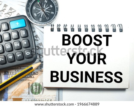 Business concept.Text BOOST YOUR BUSINESS with calculator,pencil and banknote on white background.