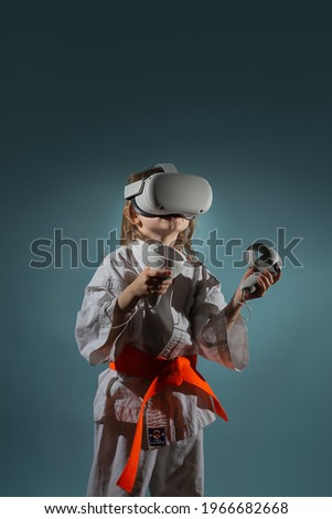 Studio Portrait of young caucasian girl in karate uniform playing video games with virtual reality headset or practicing online, embroidered text on kimono kyokushinkai.