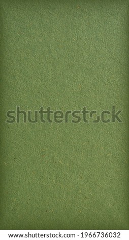 The surface of green cardboard. Mobile phone wallpaper with vignetting. Olive vertical background. Rough natural paper texture with cellulose fibers. Coloured paperboard of a calm and soft tint. Macro