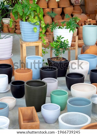 Various colorful ceramic and terracotta plant pots arranged on concrete floor. Empty geometric ceramic planter background, vertical style.