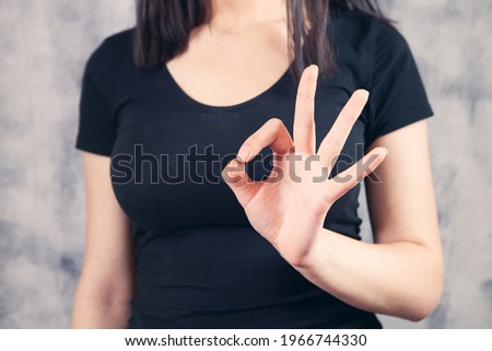 Close up image of young woman making and showing ok hand sign