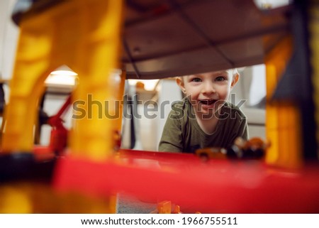 The boy smiles, happy childhood. A picture of a boy playing with toys indoors. A happy childhood in kindergarten, child development. Educating children in kindergartens, playing games and growing up