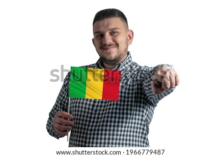 White guy holding a flag of Mali and points forward in front of him isolated on a white background.