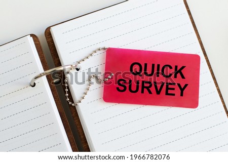 Text QUICK SURVEY on a red card that lies on an open blank notebook.
