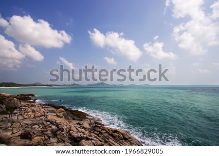 scenery of blue sky and white clouds together with sea, waves and brown rocks in foreground from south of thailand