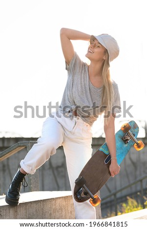 Portrait of young stylish girl wearing panama hat with a longboard in a city
