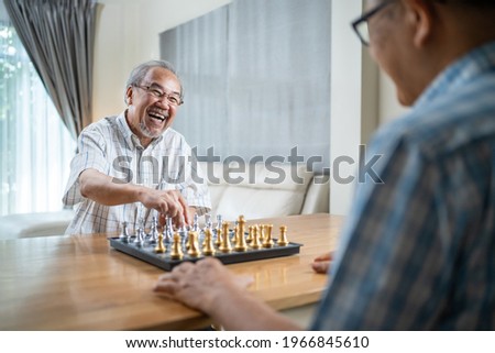 Asian Senior Elderly male spend leisure time, stay home after retirement. Happy smiling Old man enjoy activity in house playing chess game with friend together. Hospital Healthcare and medical concept Royalty-Free Stock Photo #1966845610