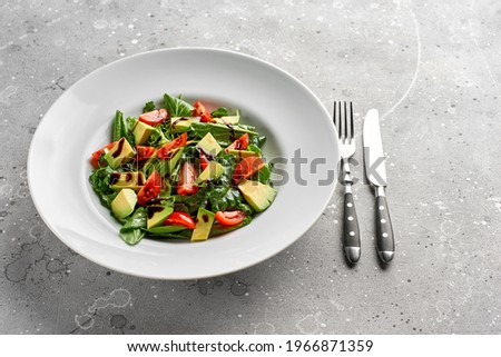 Salad with avocado, lettuce, tomato and flax seeds on gray background.Close up