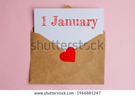 Kraft envelope with a white sheet of paper and a date 1 january, with red heart. Flat lay on pink background, romance and love concept