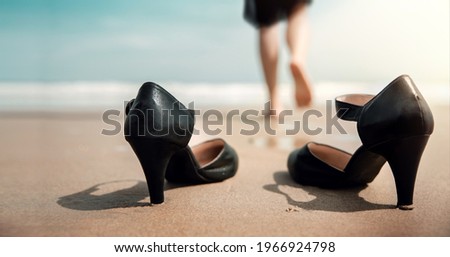 Work Life Balance Concept. Business Woman take off her Working Shoes and leave it on the Sand Beach for Walk into the Sea on Sunny Day. Quit a Job, Office Outing or Summer Vacation. Low angle View