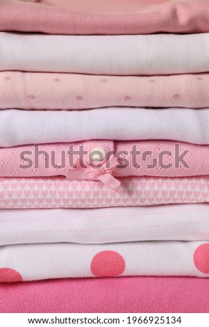 Stack of baby girl's clothes as background, closeup