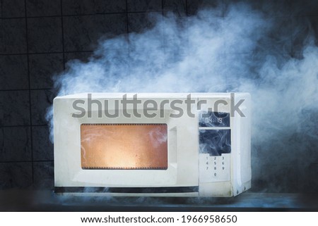 Microwave oven white, in fire front view, electrical appliances caught fire as a result of improper operation Royalty-Free Stock Photo #1966958650