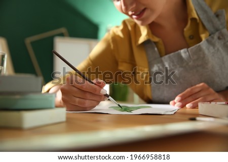 Young woman drawing leaf at table indoors, closeup