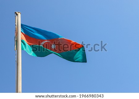 The National Flag of Azerbaijan is waving in blue sky.