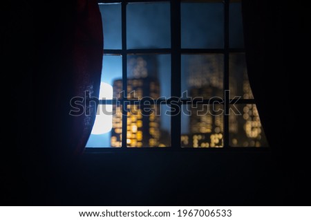 look through a window and city night view. Realistic dollhouse window and city miniature in selective focus.