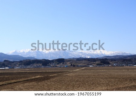 Winter snow makeup scenery of the Zao mountain range seen through rice fields (Zao Town, Katta District, Miyagi Prefecture) Royalty-Free Stock Photo #1967055199