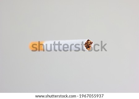 Single unlit cigarette stick with yellow filter studio close up shot isolated on white shallow depth of field