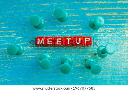 pushpins stuck into a wooden surface near the word meetup. meeting of associates