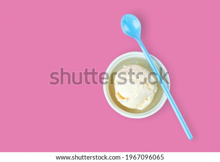 White cup of vinalla icecream and blue spoon on it serving on isolated pink background with blank copy space. Food, Dessert and advertisement Concept