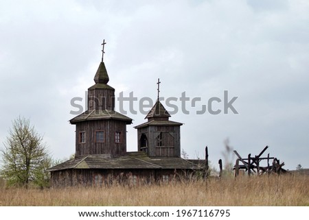 old abandoned wooden church with crosses on background of gloomy sky