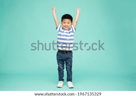 Cute Asian boy showing winner sign with his hands up isolated on green background  Royalty-Free Stock Photo #1967135329