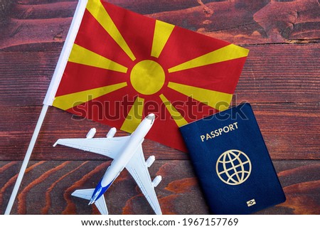 Flag of North Macedonia with passport and toy airplane on wooden background. Flight travel concept. 