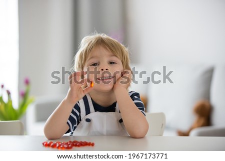 Cute little child, toddler boy, eating alfa omega 3 child supplement vitamin pills at home for better immunity Royalty-Free Stock Photo #1967173771