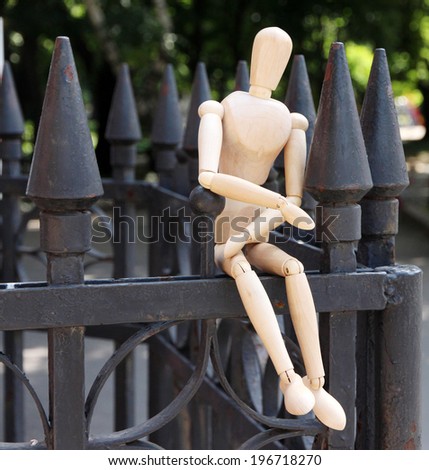 Wooden pose puppet on fence outdoors