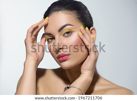 Beauty model girl with fashion make-up, Bright yellow eye line and nails, trendy manicure. Eye make-up creative ideas. Summer makeup. Beautiful young woman portrait. Face closeup Royalty-Free Stock Photo #1967211706